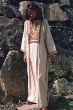 Load image into Gallery viewer, Woman in a white Gaza Dress (thobe) with red embroidery standing by boulders