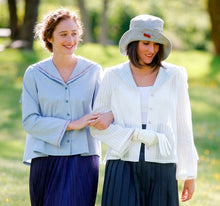 Load image into Gallery viewer, Two women walking linking arms, surrounded by greenery. Woman on the left wearing #270 Metro Middy Blouse in blue and the woman on the right is wearing a hat with the Metro Middy Blouse in white.