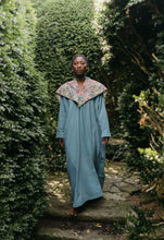 Load image into Gallery viewer, Black woman walking toward camera wearing a long blue dress with an embroidered triangular collar yoke.