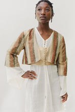 Load image into Gallery viewer, Black woman standing with hand on her hip in front of a white background. She is wearing a white long sleeve entari, an embroidered gold vest, and a striped long sleeve jacket.