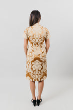 Load image into Gallery viewer, Asian woman wearing a gold brocade knee-length cheogsam - back view in front of a white back ground..