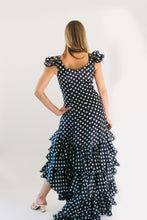 Load image into Gallery viewer, Photo of back view of woman wearing the Flamenco dress. She stands in front of a white studio backdrop and has her left hand on her hip.