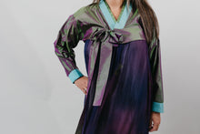 Load image into Gallery viewer, Woman wearing a purple shot silk han bok dress and jacket. Jacket is of teal and green shot silk and tied in the front. She is standing in front of a white backdrop. Photo is a close up of the front of the hanbok