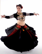Load image into Gallery viewer, Woman wearing a full black skirt, tasseled belt, cropped long sleeve black choli and coin bra. She is spinning and the skirt is flaring out and her hands are out to the side. She is a belly dancer.