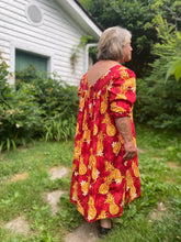 Load image into Gallery viewer, Older woman wearing a red muumuu with yellow pineapples on it. Sleeves are 3/4 length and she walking away from the camera.