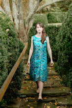 Load image into Gallery viewer, Woman walking down stone steps outside in a sleeveless teal brocade muumuu.