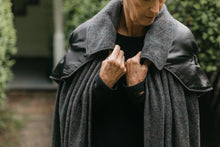 Load image into Gallery viewer, Close up of older white woman standing surrounded by greenery wearing 207 Kinsale Cloak holding the each side of the collar with hands close to chest.