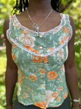 Load image into Gallery viewer, close up of front of sleeveless camisole in floral green and orange, worn by an african american woman with braided hair.