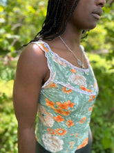 Load image into Gallery viewer, close up of side of sleeveless camisole in floral green and orange, worn by an african american woman with braided hair.