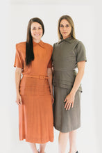 Load image into Gallery viewer, Two women standing in 1930s Day Dresses. Both are looking forward and standing in front of a white backdrop. Dress on left is a light salmon color. On right is a tan color. Botha re wearing view A. View A features round neck with collar points and peplum cleverly cut on the straight grain but with the slimming look of a bias cut.