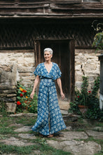 Load image into Gallery viewer, Woman walking in beach pyjamas outdoors in front of stone building with flowers by door.