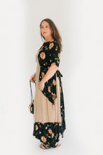 Load image into Gallery viewer, A brunette woman standing in front of a white studio backdrop, turned to the side wearing #261 Paris Promenade Dress, holding a handbag.