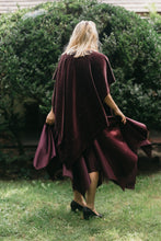 Load image into Gallery viewer, Back view of young blonde white woman standing surrounded by greenery wearing the Monte Carlo dress and V-Neck Tunic in maroon.