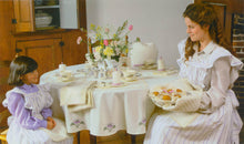 Load image into Gallery viewer, A young girl and woman sitting at a table with the tea . egg and biscuit cozy as well as the table cloth, napkins and placemats on the table. Both people are wearing the apron in a white and blue striped fabric looking at each other.