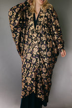 Load image into Gallery viewer, Front view of a young white blond woman standing in front of a studio gray backdrop wearing the Poiret Cocoon Coat