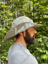 Load image into Gallery viewer, Person wearing a wide-brimmed grey hat outdoors with greenery in the background