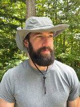 Load image into Gallery viewer, Man wearing a wide-brimmed grey hat and grey tshirt outdoors with greenery in the background