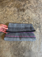 Load image into Gallery viewer, fabric clutch with striped pattern held by a hand on a concrete surface