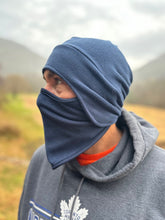 Load image into Gallery viewer, Person wearing a blue balaclava and gray hoodie with a logo in an outdoor setting