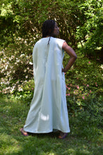 Load image into Gallery viewer, Back of African American woman standing with hang on her hip with greenery in the background.