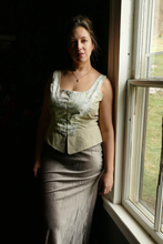 Load image into Gallery viewer, white woman standing next to window in sleevless corset top in light colored patterned fabric and skirt showing pattern use for women's corset top pattern make it yourself for cottagecore or romantic look