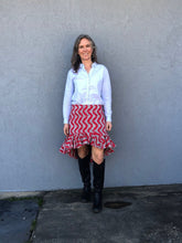 Load image into Gallery viewer, Woman standing in front of a grey wall outside, wearing a buttondown shirt with the Flamenco practice skirt and black boots. Skirt is red and white ankara fabric and is above the knee in the front and top of calf in the back with a ruffled flounce.