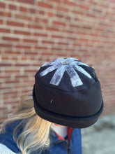 Load image into Gallery viewer, Black and white snowflake-patterned hat worn against a brick wall.