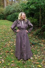 Load image into Gallery viewer, A woman wearing a brown Calico Day Dress standing in lawn outside with her hands on her hips.