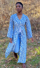 Load image into Gallery viewer, Black woman wearing a long grey blue batiked entari, walking outside.
