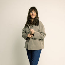 Load image into Gallery viewer, Woman wearing a beige jacket and blue pants on a plain background