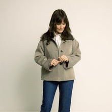 Load image into Gallery viewer, Woman wearing a beige coat and blue jeans on a plain background