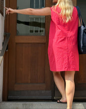 Load image into Gallery viewer, Woman in a red dress standing at a wooden door
