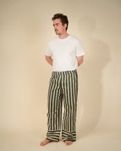 Load image into Gallery viewer, A man stands barefoot against a plain beige studio background, wearing a plain white short-sleeve t-shirt and loose vertical green-and-white striped pants.