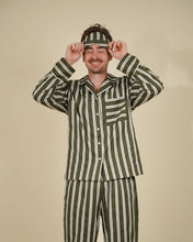 Load image into Gallery viewer, A man wearing a matching green and white vertically striped pajama set with a headband, posing with his hands on the headband against a solid beige background.