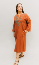 Load image into Gallery viewer, Woman in coral Egyptian Shirt.  Long version coral color with one hand in pocket.  Photo with white background.
