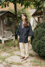 Load image into Gallery viewer, Japanese American woman in a navy Hippari and cream pants standing by shrubs outside.
