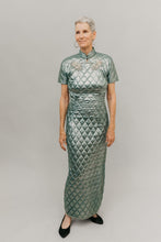 Load image into Gallery viewer, Photo of woman in ankle length 122 Hong Kong Cheongsam.  Fabric is a quilted shinny light green with ornate metallic frog closures.

