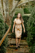 Load image into Gallery viewer, Asian woman wearing a gold brocade knee-length cheogsam walking down stone steps outside.
