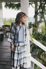 Load image into Gallery viewer, Young girl in a plaid kimono standing on a wooden deck with greenery in the background
