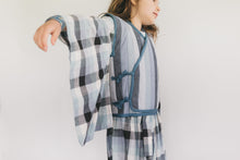 Load image into Gallery viewer, Girl wearing a plaid kimono-style garment against a plain background

