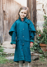 Load image into Gallery viewer, Young girl wearing a blue Australian Drovers Coat. standing out side in front of a wooden building.

