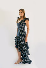 Load image into Gallery viewer, Woman standing in front of white studio backdrop wearing Dark Blue with white polka dots140 Flamenco Dress.  Woman stands with her arms by her side and is slightly turned to the right.

