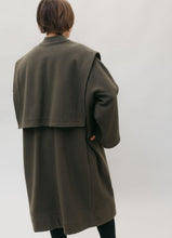 Load image into Gallery viewer, White woman standing with her hands in the pockets of a large dark olive green szur.  Her back is to the camera.
