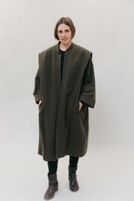 Load image into Gallery viewer, White woman standing with her hands in the pockets of a large dark olive green szur.
