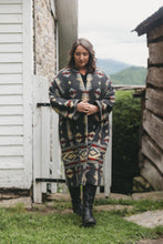 Load image into Gallery viewer, woman walking outside wearing a Hungarian Szur made of heavy wool. Szur is contemporary view B.
