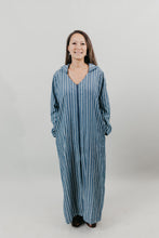 Load image into Gallery viewer, Asian woman wearing a floor length blue and white vertical striped Djellaba with her hands in her pockets.  Background is white back drop.
