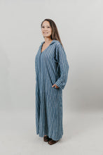 Load image into Gallery viewer, Asian woman wearing a floor length blue and white vertical striped Djellaba with her hands in her pockets.  She is turned slightly to the side.Background is white back drop.
