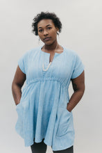Load image into Gallery viewer, African American woman wearing the women's Ghanaian Smock in light blue with hands in pockets.

