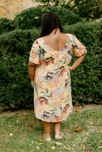 Load image into Gallery viewer, Back view of Black woman wearing a size 2XL knee-length, short-sleeve, yellow muumuu with orange and green palm fronds on it.
