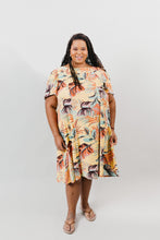 Load image into Gallery viewer, Black woman with long thin dreds, wearing a size 2XL knee-length, short-sleeve, yellow muumuu with orange and green palm fronds on it.  Background is white back drop.
